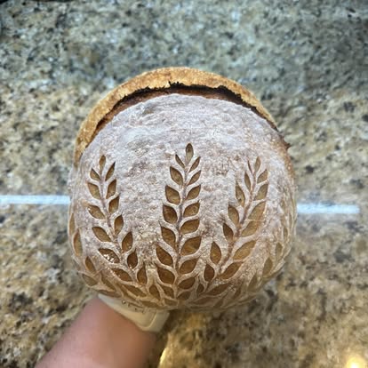 A round traditional sourdough loaf with wheat scoring.